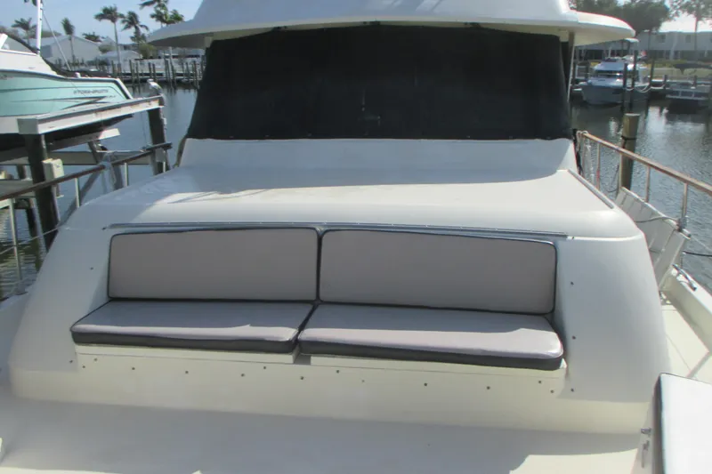 Slide: The Image of 1981 Hatteras 61 Motor Yacht with cushioned seating on deck, docked at marina. - 8