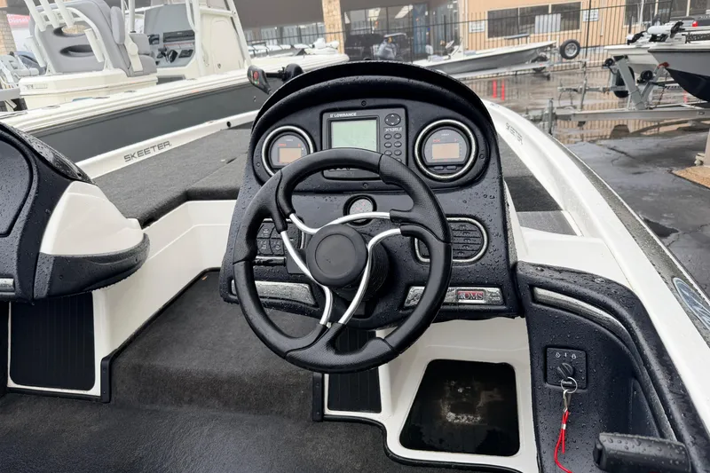 Slide: The Image of 2006 Skeeter 20i boat dashboard with steering wheel and controls, wet from rain. - 9