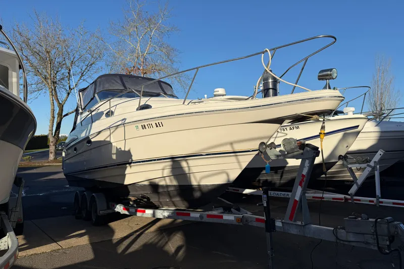 The Image of 2000 Regal Commodore 2760 boat on trailer, parked outdoors under clear blue sky. - 1