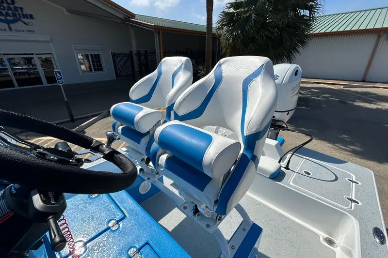 Slide: The Image of 2026 Gulf Coast Saber Cat boat with blue and white seating, parked outdoors. - 12