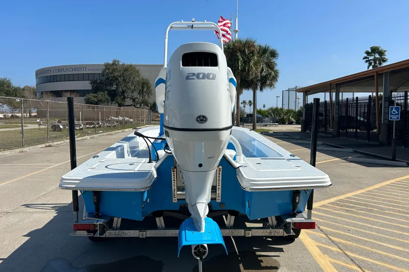 Slide: The Image of 2026 Gulf Coast Saber Cat boat with powerful outboard motor, parked outdoors. - 6