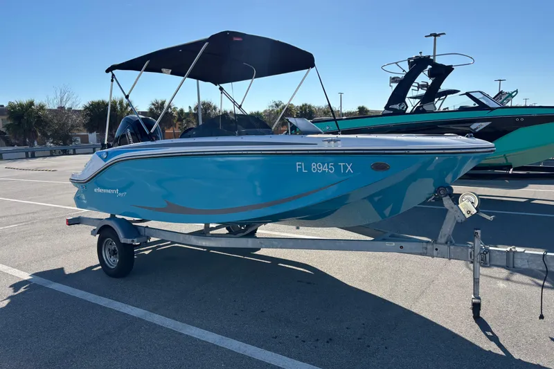 The Image of 2023 Bayliner Element M17 boat on trailer, blue hull, parked in sunny lot. - 0