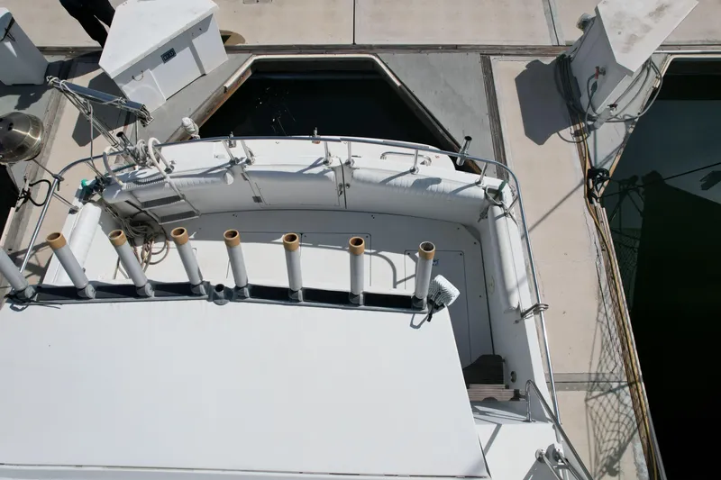 Slide: The Image of 1989 Carver 3297 Mariner boat docked, featuring fishing rod holders and deck equipment. - 17