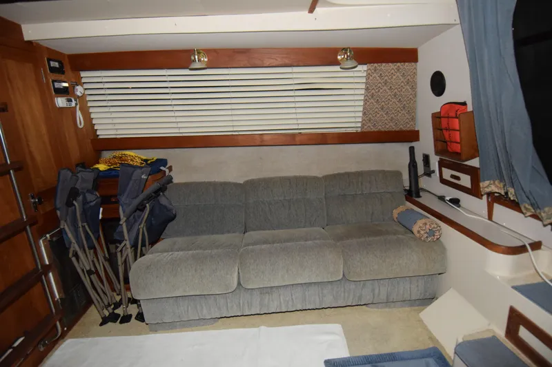 Slide: The Image of Interior of 1989 Carver 3297 Mariner with gray sofa, folding chairs, and nautical decor. - 4