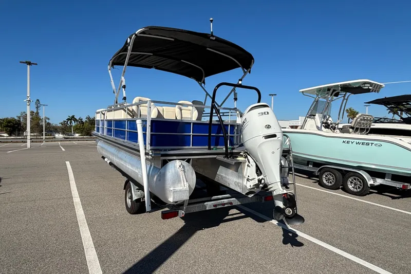 Slide: The Image of 2023 Lexington 321 Fish pontoon boat with canopy and outboard motor in parking lot. - 4