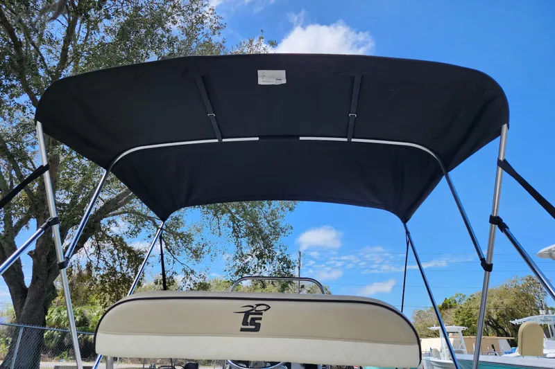 Slide: The Image of 2022 Carolina Skiff 178 JLS boat with black canopy under blue sky. - 11