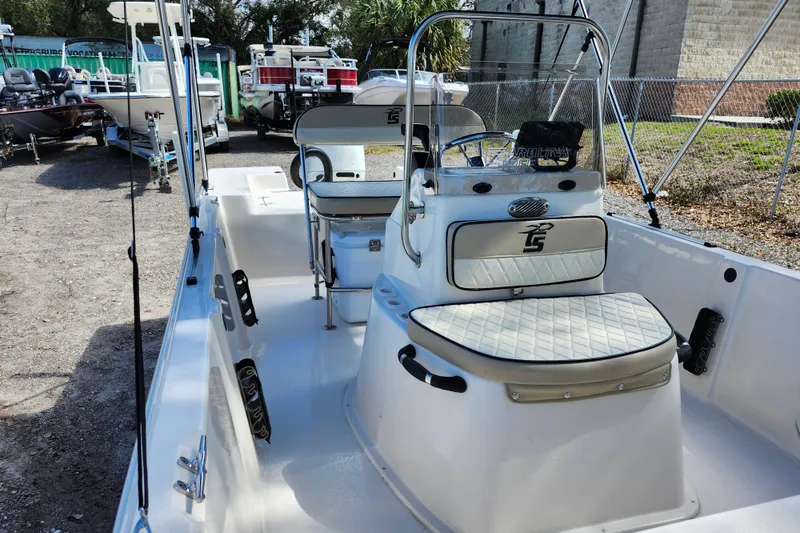 Slide: The Image of 2022 Carolina Skiff 178 JLS boat interior with seating and console, parked outdoors. - 16