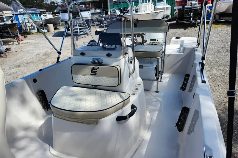 Slide: The Image of 2022 Carolina Skiff 178 JLS boat interior with seating and console, parked outdoors. - 17