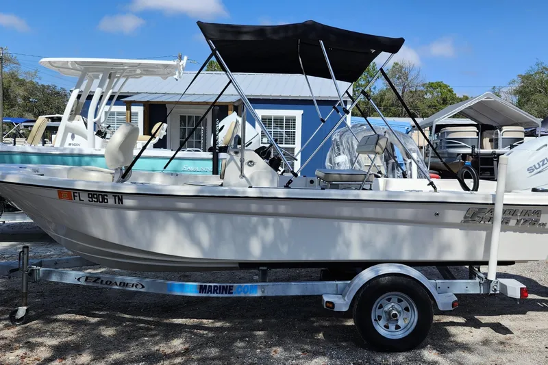 Slide: The Image of 2022 Carolina Skiff 178 JLS boat on trailer with canopy, parked outdoors. - 3