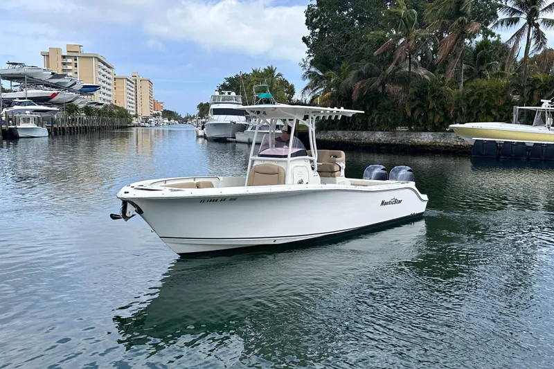 Slide: The Image of 2020 NauticStar 25 XS boat cruising in a scenic canal with palm trees. - 11