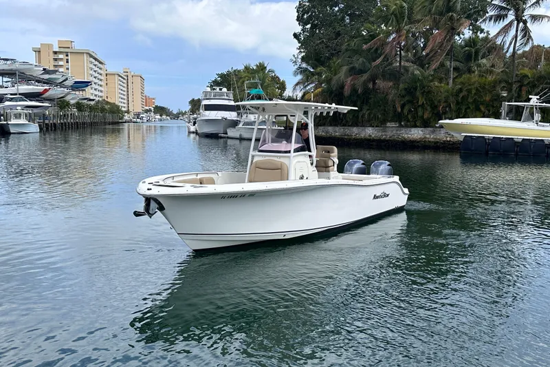 Slide: The Image of 2020 NauticStar 25 XS boat cruising in a scenic canal with palm trees. - 12