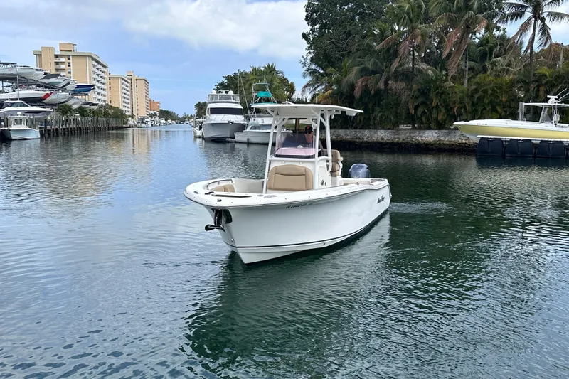 Slide: The Image of 2020 NauticStar 25 XS boat cruising in a scenic canal with palm trees. - 14