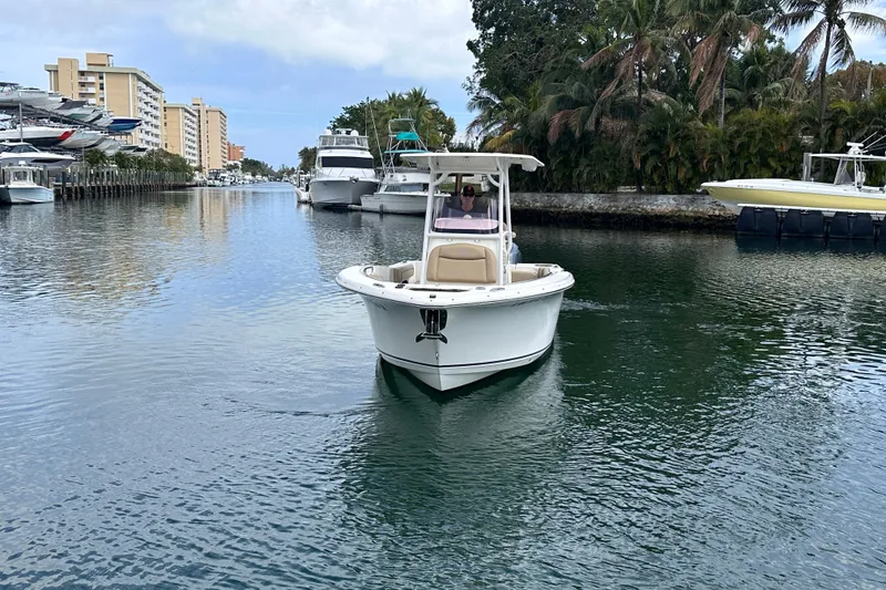 Slide: The Image of 2020 NauticStar 25 XS boat cruising in a scenic canal with palm trees. - 16