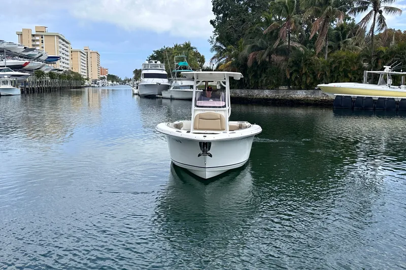 Slide: The Image of 2020 NauticStar 25 XS boat cruising in a scenic canal with palm trees. - 17