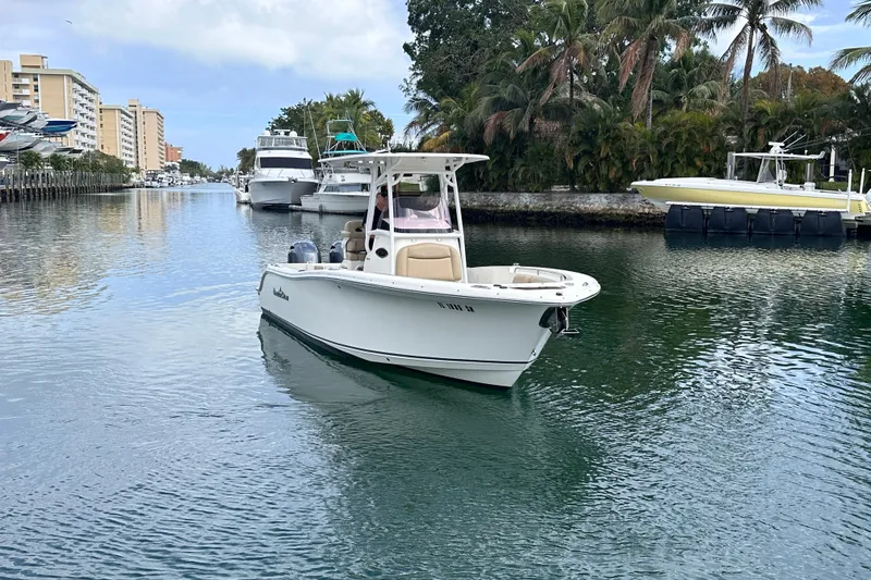 Slide: The Image of 2020 NauticStar 25 XS boat cruising in a scenic canal with palm trees. - 20