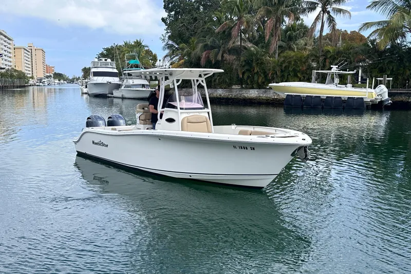 Slide: The Image of 2020 NauticStar 25 XS boat cruising on a scenic waterway with palm trees. - 22