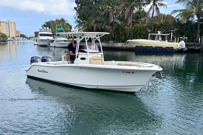 Slide: The Image of 2020 NauticStar 25 XS boat cruising on a scenic waterway with palm trees. - 23