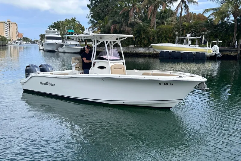 Slide: The Image of 2020 NauticStar 25 XS boat cruising on a scenic waterway with palm trees. - 24