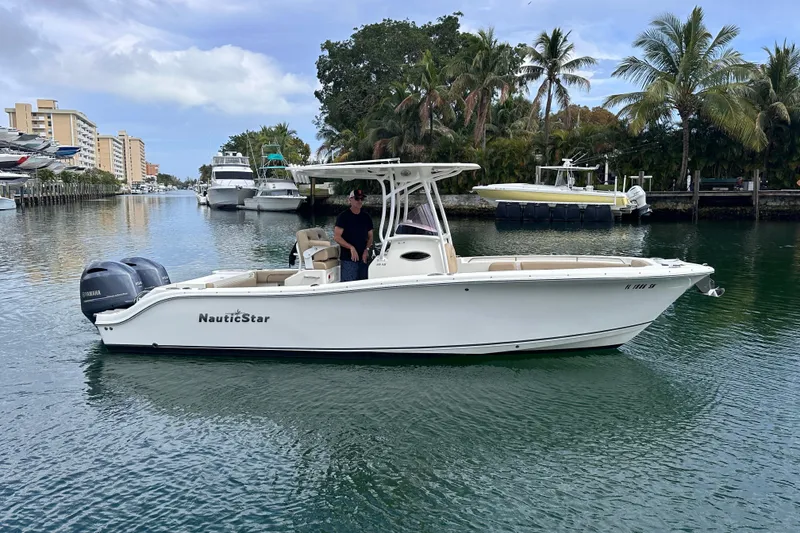 Slide: The Image of 2020 NauticStar 25 XS boat cruising on a scenic waterway with palm trees. - 25