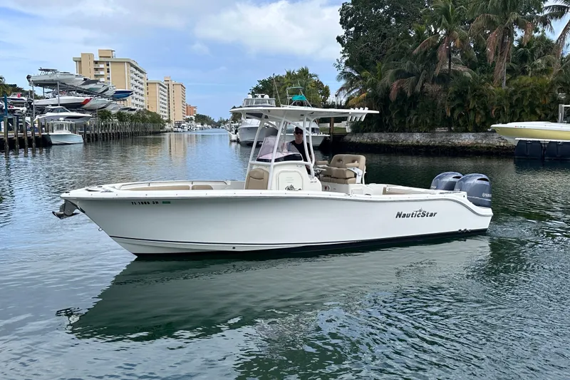 Slide: The Image of 2020 NauticStar 25 XS boat cruising on a calm waterway with palm trees. - 3