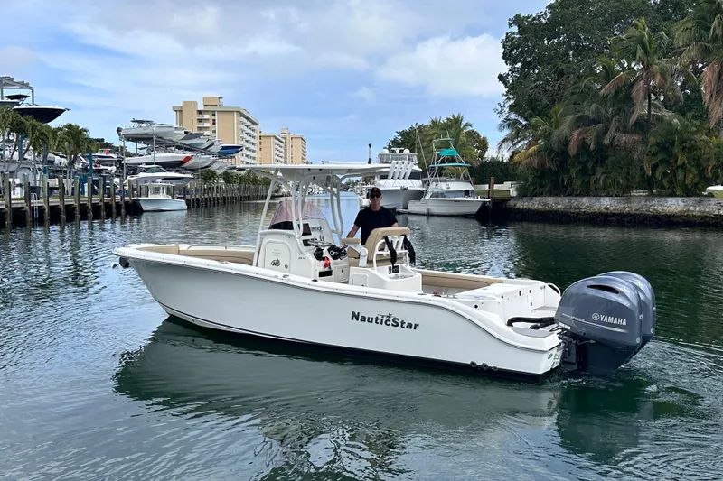 Slide: The Image of 2020 NauticStar 25 XS boat cruising in a scenic marina with palm trees. - 4