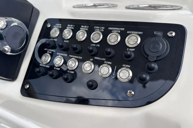 Slide: The Image of Control panel of 2020 NauticStar 25 XS boat with various switches and 12V outlet. - 43