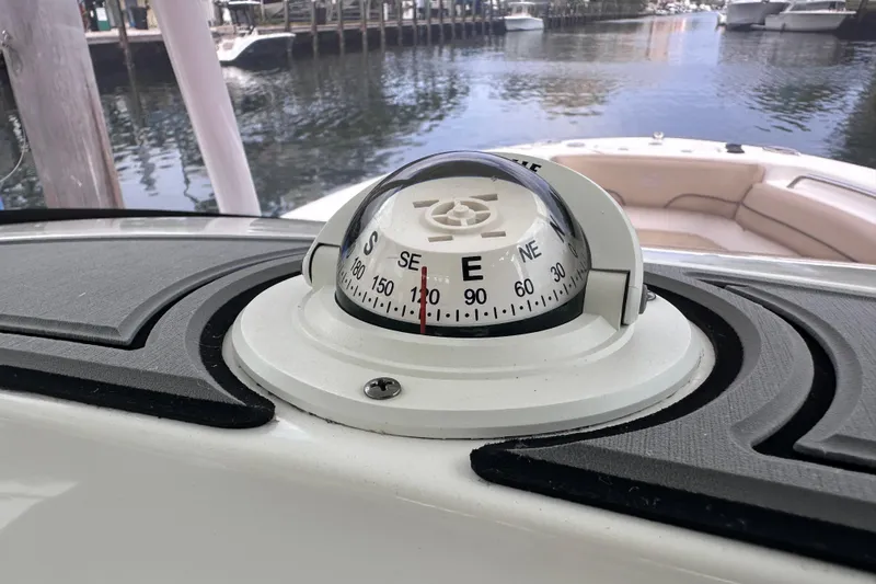 Slide: The Image of 2020 NauticStar 25 XS boat compass on dashboard, docked by the water. - 48
