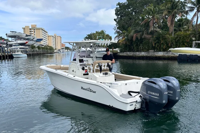 Slide: The Image of 2020 NauticStar 25 XS boat with dual Yamaha engines cruising in a scenic waterway. - 5