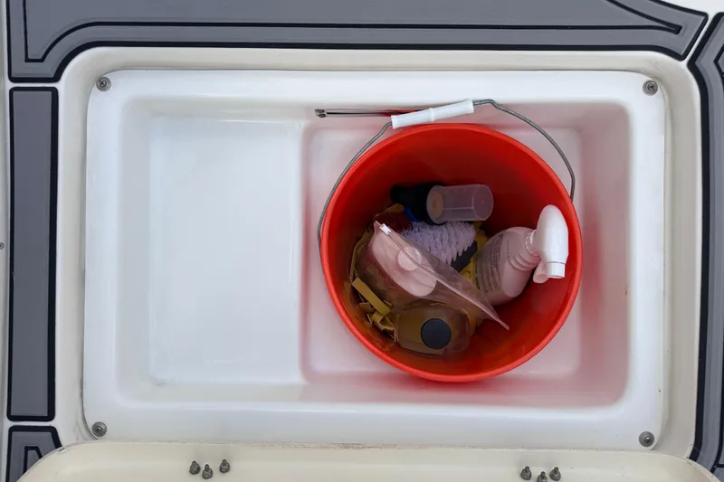Slide: The Image of Red bucket with cleaning supplies in NauticStar 25 XS boat compartment, 2020 model. - 52