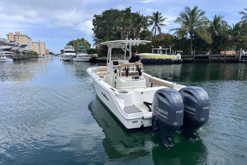 Slide: The Image of 2020 NauticStar 25 XS boat with dual Yamaha engines cruising in a scenic waterway. - 6