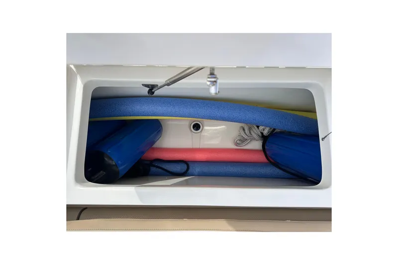Slide: The Image of Storage compartment of 2020 NauticStar 25 XS boat with pool noodles and gear. - 88
