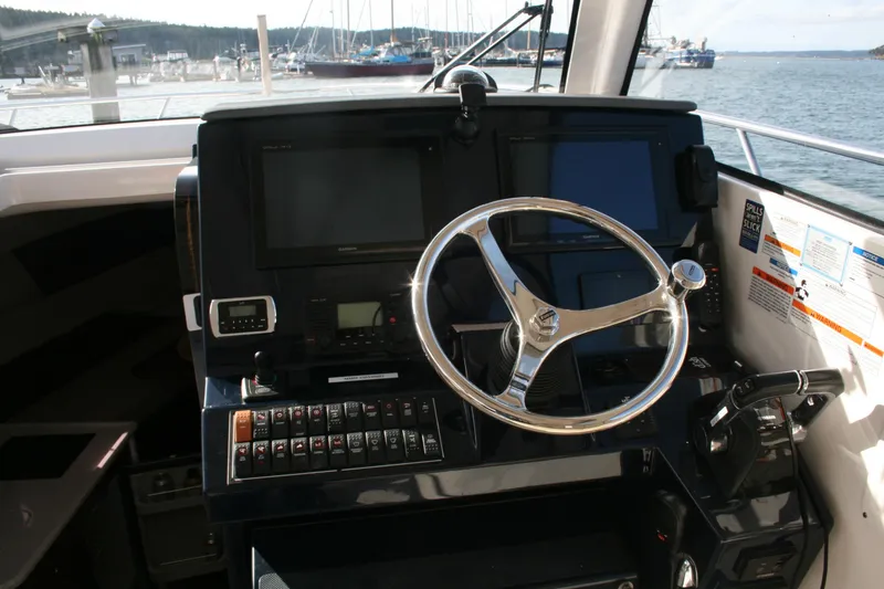 Slide: The Image of 2016 Pursuit OS 325 Offshore boat helm with steering wheel and navigation controls. - 11