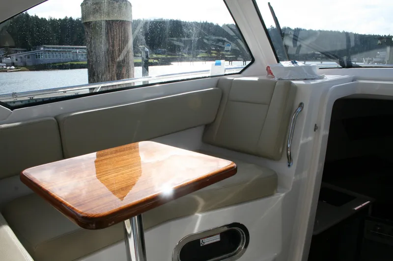 Slide: The Image of Interior of 2016 Pursuit OS 325 Offshore boat with wooden table and cushioned seating. - 14