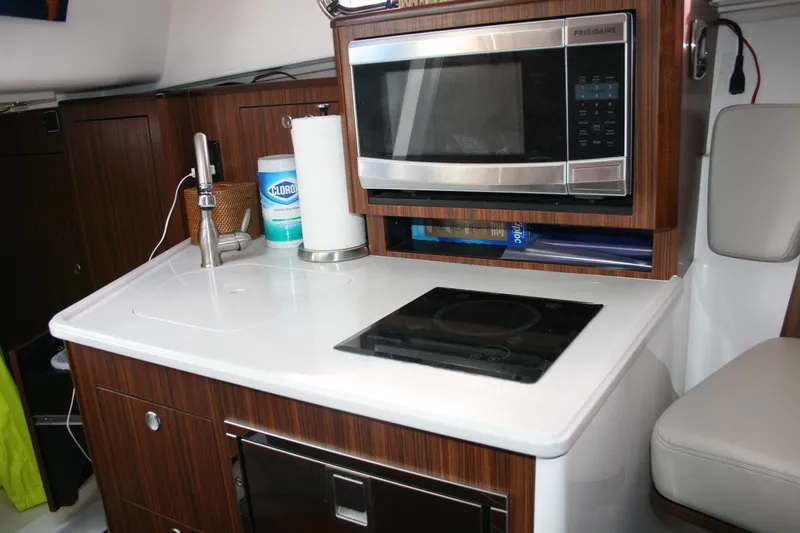 Slide: The Image of 2016 Pursuit OS 325 Offshore yacht kitchen with microwave, sink, and stove. - 15
