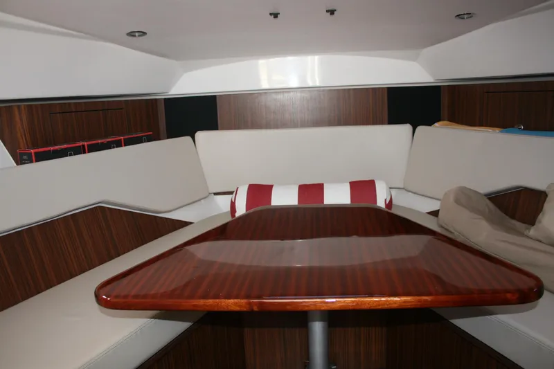 Slide: The Image of 2016 Pursuit OS 325 Offshore cabin interior with wooden table and cushioned seating. - 16