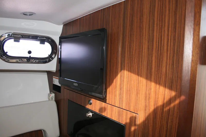 Slide: The Image of 2016 Pursuit OS 325 Offshore cabin interior with TV and wood paneling. - 17