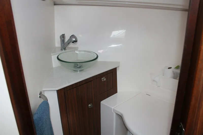 Slide: The Image of 2016 Pursuit OS 325 Offshore boat bathroom with glass sink and wooden cabinet. - 18