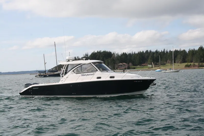 Slide: The Image of 2016 Pursuit OS 325 Offshore boat on calm water, surrounded by sailboats. - 2