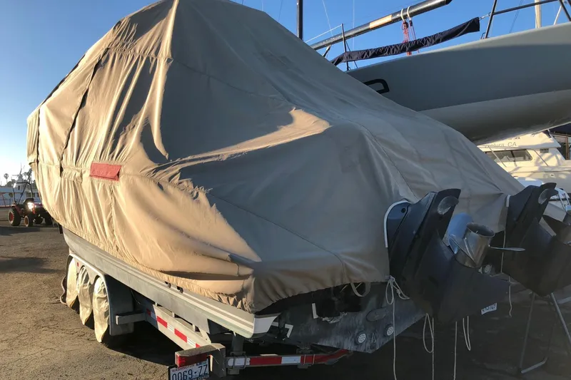 Slide: The Image of 2016 Pursuit OS 325 Offshore boat covered on trailer, parked outdoors. - 21