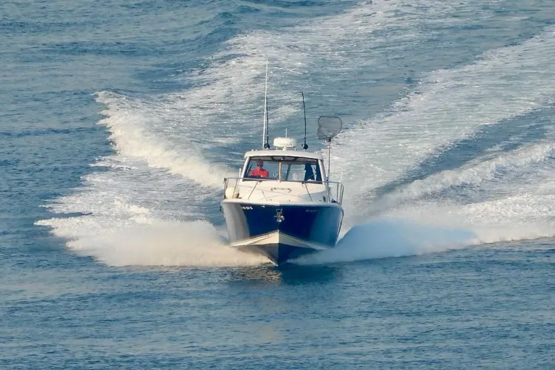 Slide: The Image of 2016 Pursuit OS 325 Offshore boat cruising on open water, creating a wake. - 7