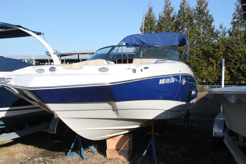 The Image of 2018 NauticStar 243DC Sport Deck boat on stands, blue and white exterior. - 1