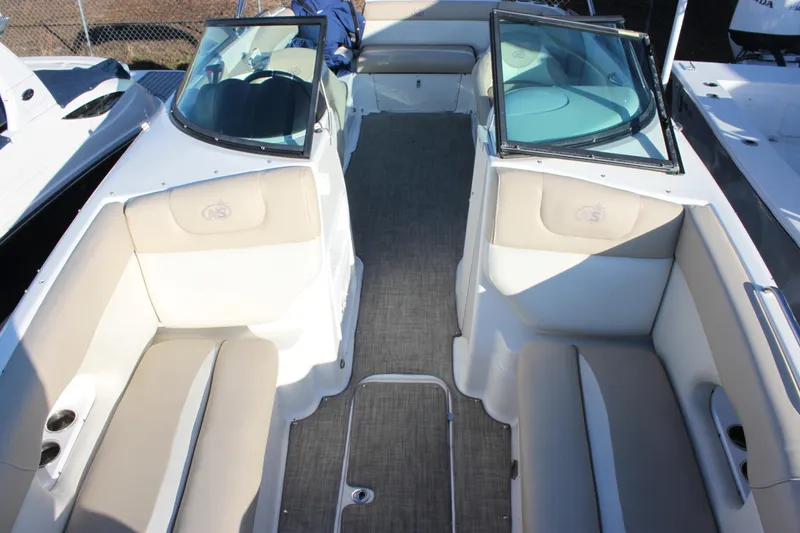 Slide: The Image of 2018 NauticStar 243DC Sport Deck interior with beige seating and dual consoles. - 11