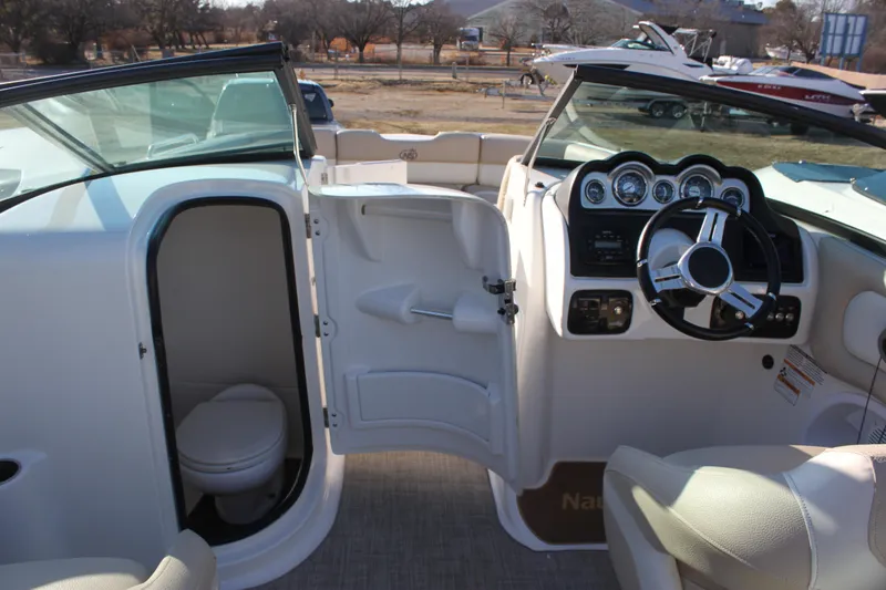 Slide: The Image of 2018 NauticStar 243DC Sport Deck interior with helm and cabin door open. - 12