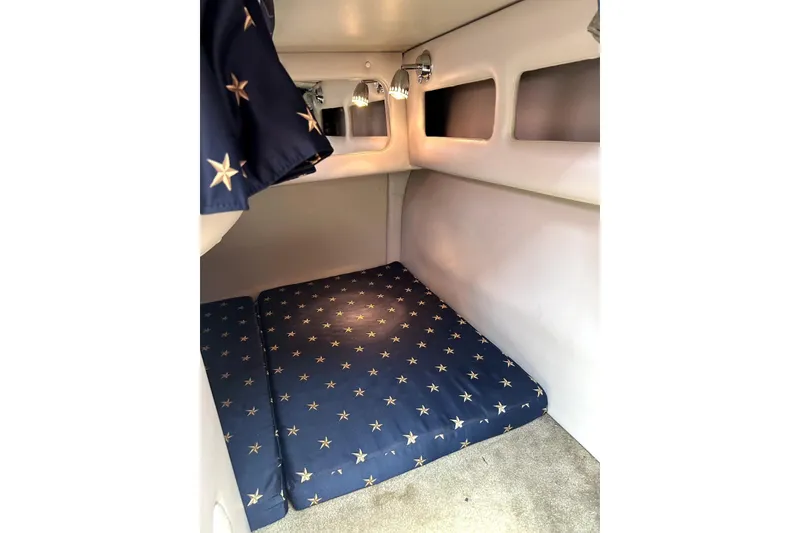 Slide: The Image of 2012 Crownline 260 CR cabin interior with star-patterned bedding and cozy lighting. - 20