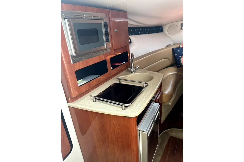 Slide: The Image of 2012 Crownline 260 CR boat interior with kitchenette, featuring microwave, sink, and mini-fridge. - 21