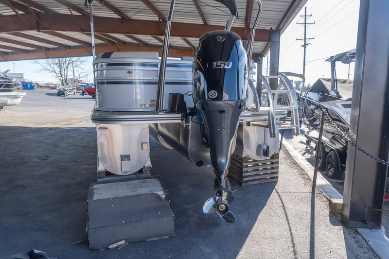 Slide: The Image of 2026 SunCatcher Select 322RC pontoon boat with powerful outboard motor in covered storage. - 2