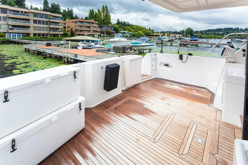Slide: The Image of 2004 West Bay Sonship yacht deck with wooden flooring, docked near waterfront homes. - 23