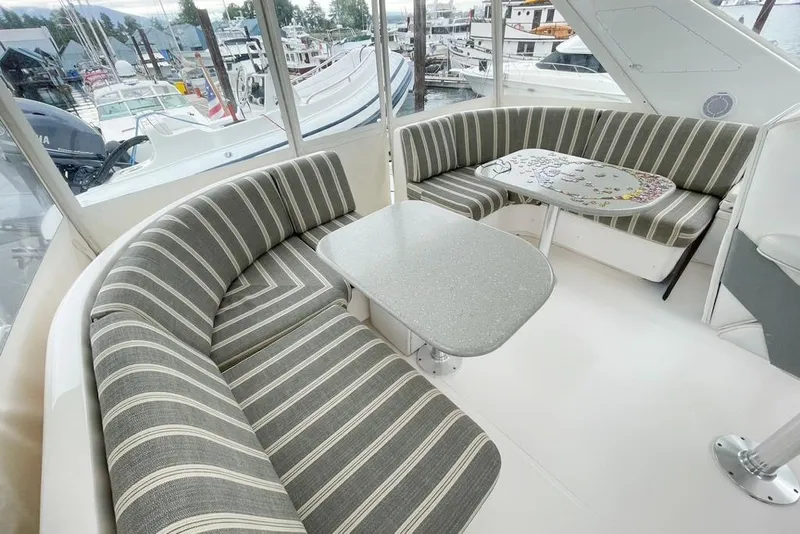 Slide: The Image of 2004 West Bay Sonship yacht interior with striped seating and table, docked at marina. - 26