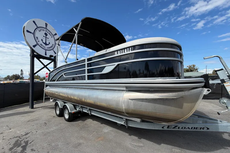 The Image of 2023 Lowe SS 210 pontoon boat on trailer under a clear blue sky. - 0
