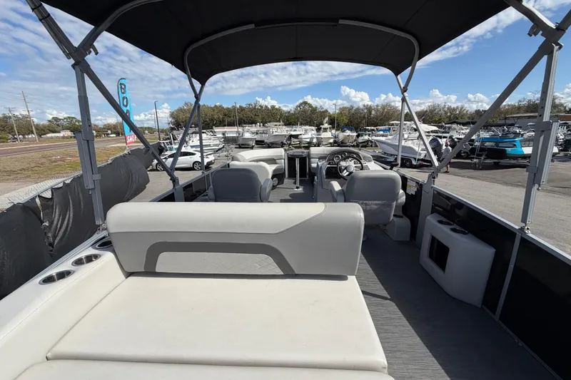Slide: The Image of 2023 Lowe SS 210 pontoon boat interior with seating and steering console, displayed outdoors. - 16